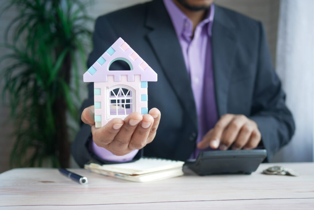 Man holding a calculator and a house. Home loan pre-approvals give you an insight about how much house you can afford.